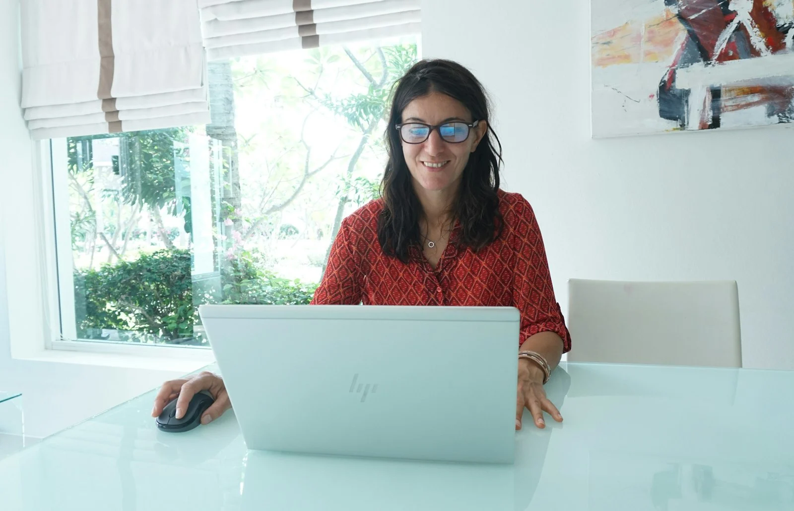 Lächelnde Frau arbeitet an einem Laptop an einem hellen Tisch